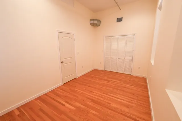 a view of empty room with wooden floor and fan