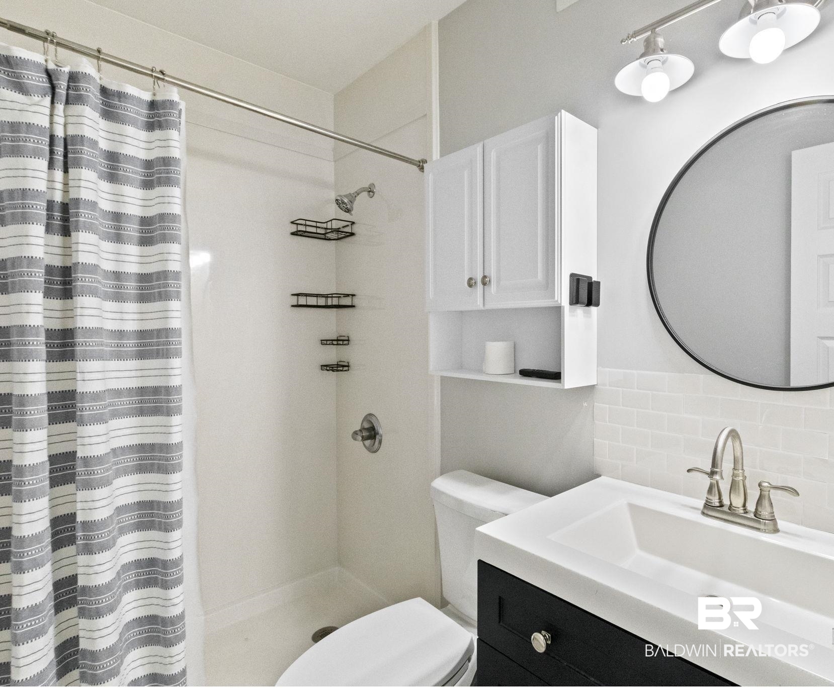 25861 Canal Road, Unit 77 Orange Beach, AL 36561 - Photo 29 of 48 Bathroom featuring decorative backsplash, vanity, and a stall shower
