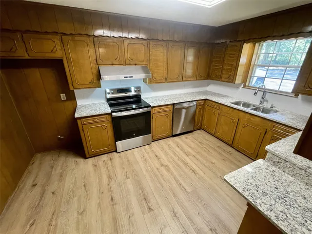 a kitchen with granite countertop a sink dishwasher stove and cabinets
