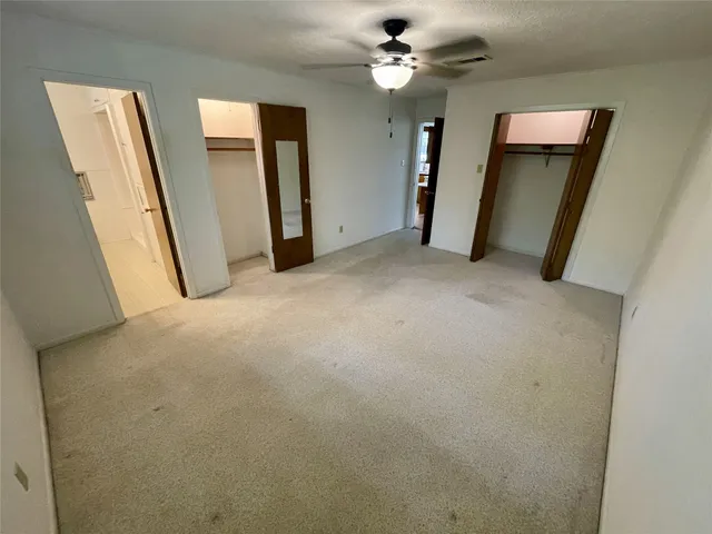 a view of a hallway with closet and a chandelier fan