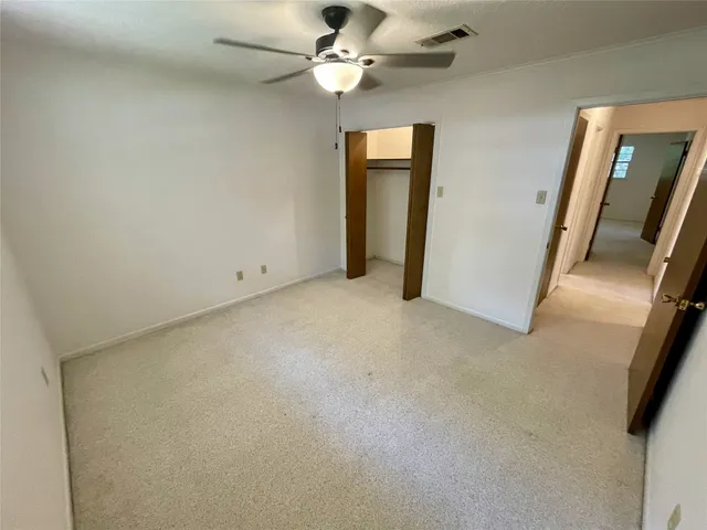 an empty room with closet and a ceiling fan