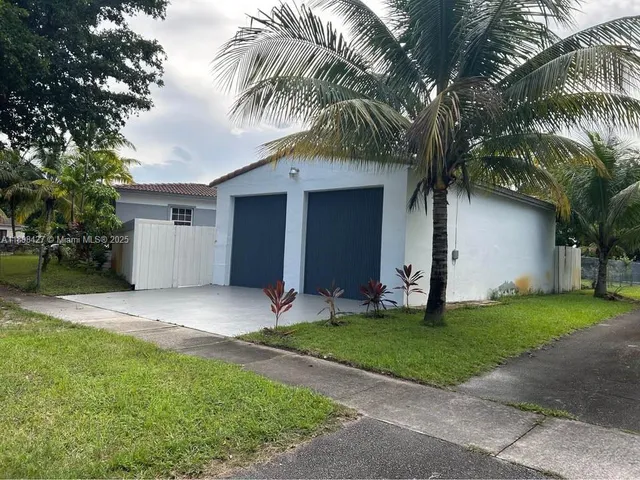 a view of a house with a yard and palm trees