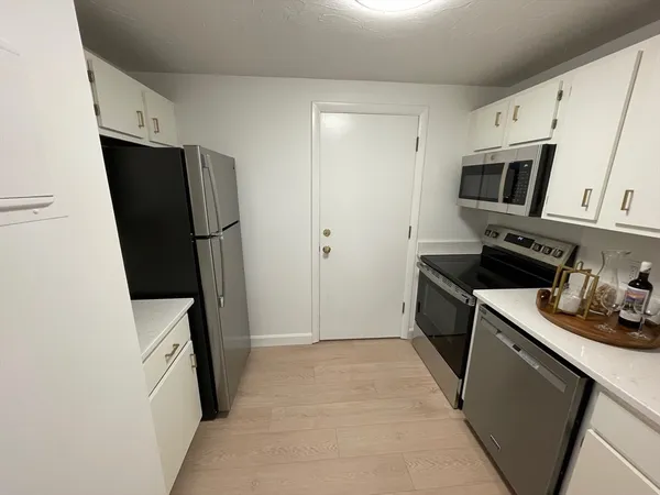 a kitchen with stainless steel appliances a refrigerator a sink a stove and white cabinets