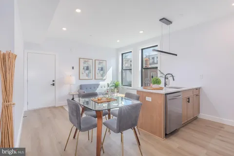 a kitchen with stainless steel appliances granite countertop a dining table chairs and white cabinets