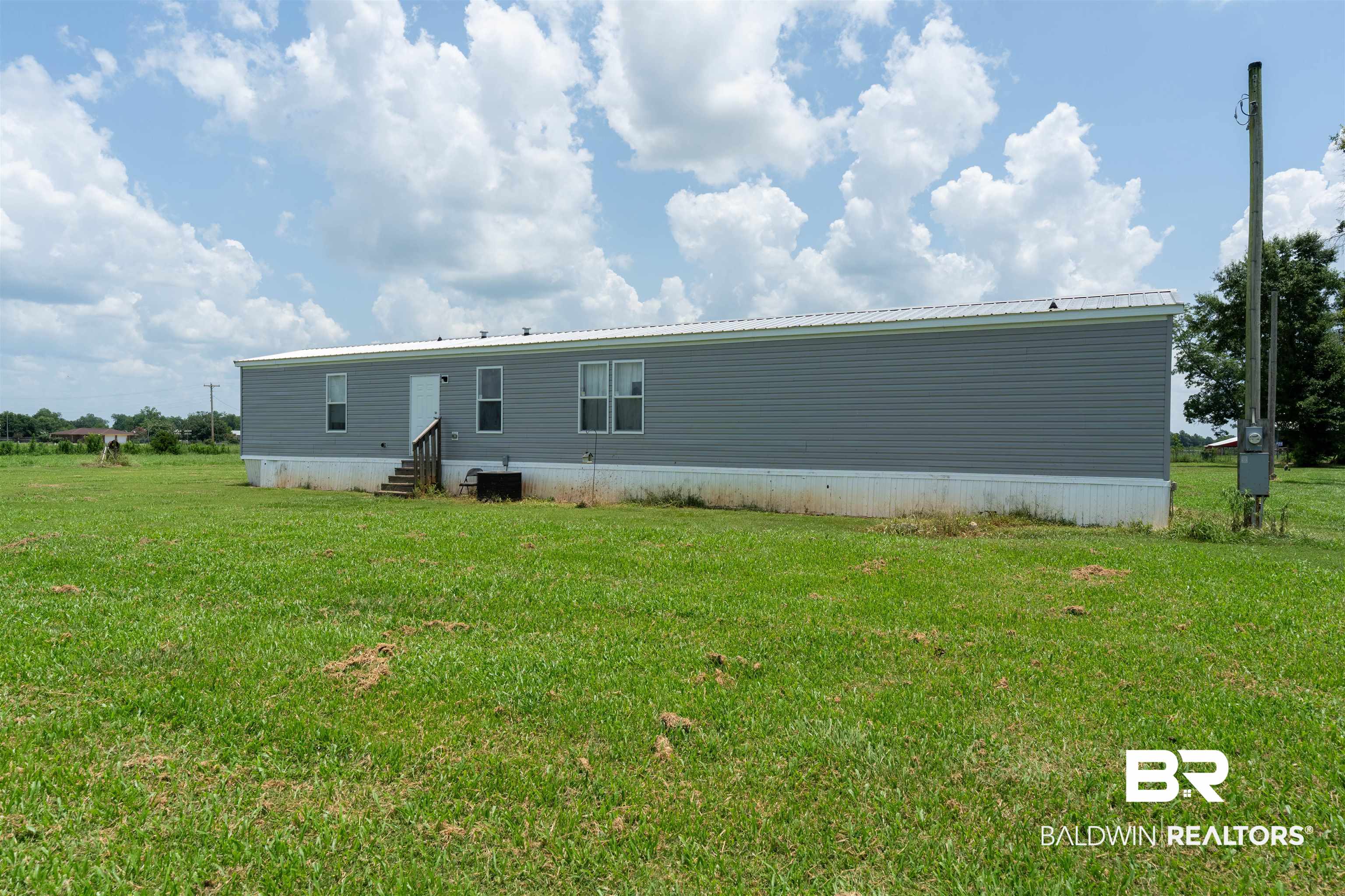 15575 Mikkelsen Road Summerdale, AL 36580 - Photo 26 of 68 Exterior featuring gray horizontal siding, a white trim, and a white metal roof