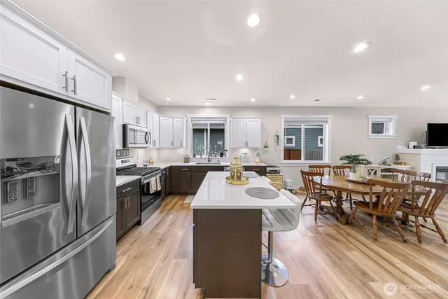 a large kitchen with a large counter top a sink appliances and dining table