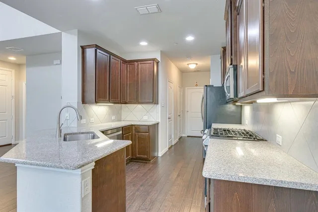 a kitchen with stainless steel appliances granite countertop a sink and a refrigerator