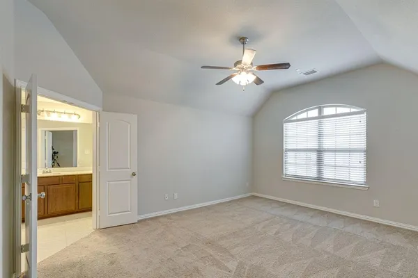 an empty room with chandelier fan and windows