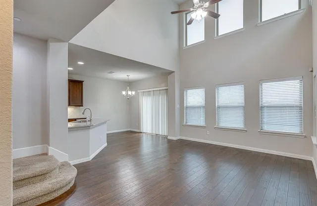an empty room with wooden floor and kitchen view