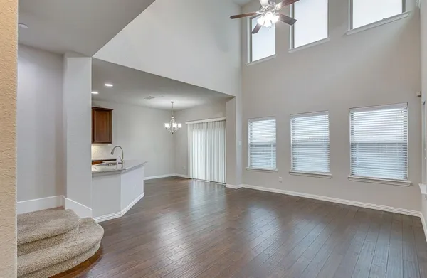 an empty room with wooden floor and kitchen view