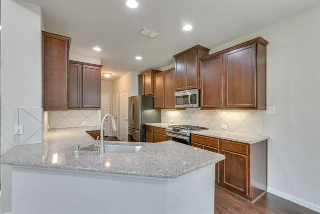 a kitchen with kitchen island granite countertop wooden cabinets a sink and dishwasher