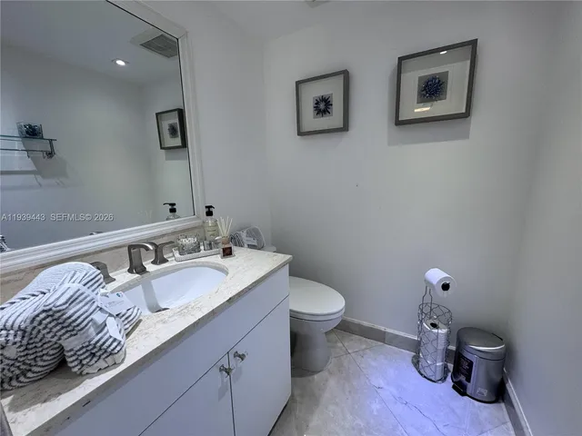 a bathroom with a granite countertop toilet and a sink