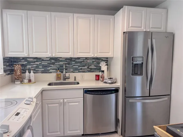 a kitchen with a sink a refrigerator and cabinets