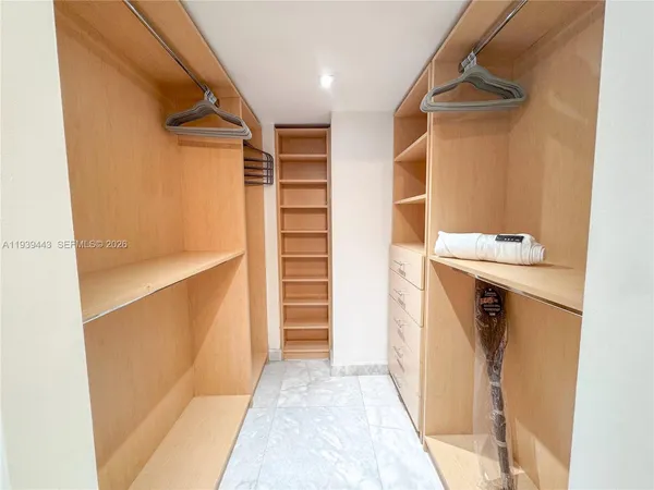 a view of walk in closet with clothes and shoes