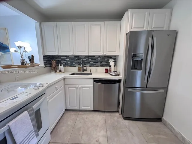 a kitchen with a refrigerator sink and cabinets