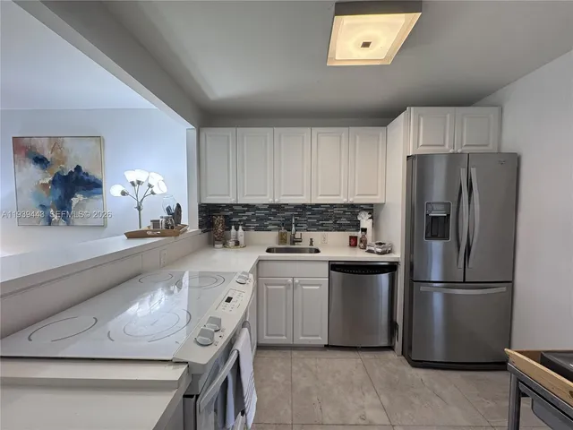 a kitchen with a refrigerator a stove top oven a sink and cabinets