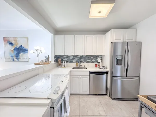 a kitchen with a refrigerator sink and white cabinets