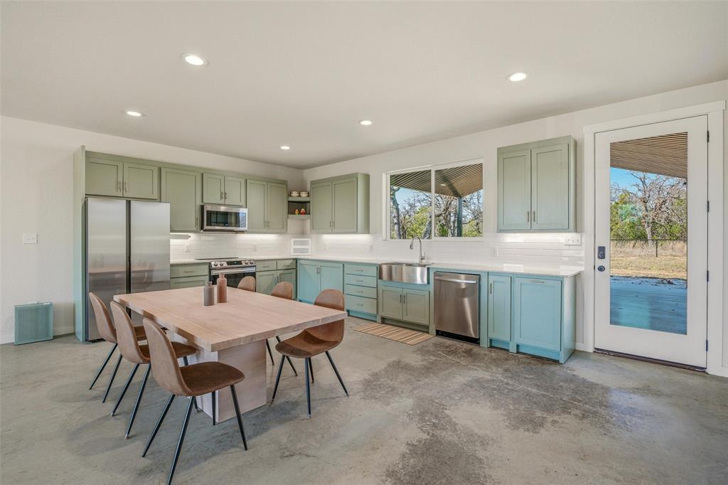 1525 North Bosley Road Santo, TX 76472 - Photo 12 of 40 a kitchen with kitchen island a dining table chairs and refrigerator