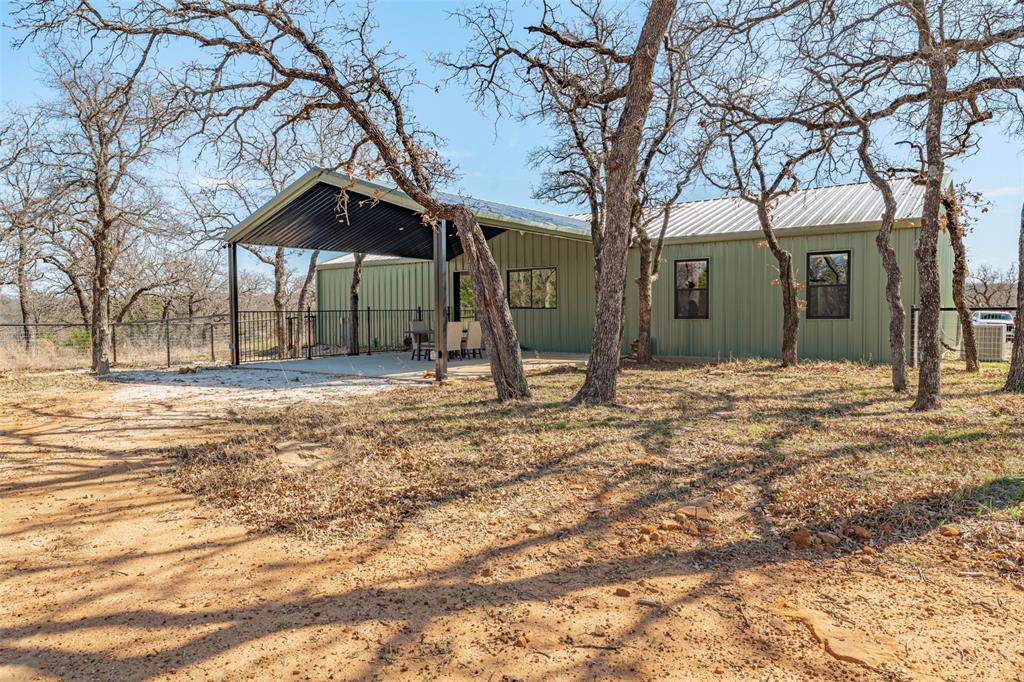 1525 North Bosley Road Santo, TX 76472 - Photo 31 of 40 a backyard of a house with large trees and outdoor seating