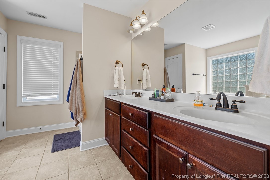 1365 Micahs Way North Spring Lake, NC 28390 - Photo 23 of 36 a bathroom with a double vanity sink a mirror and a bathtub