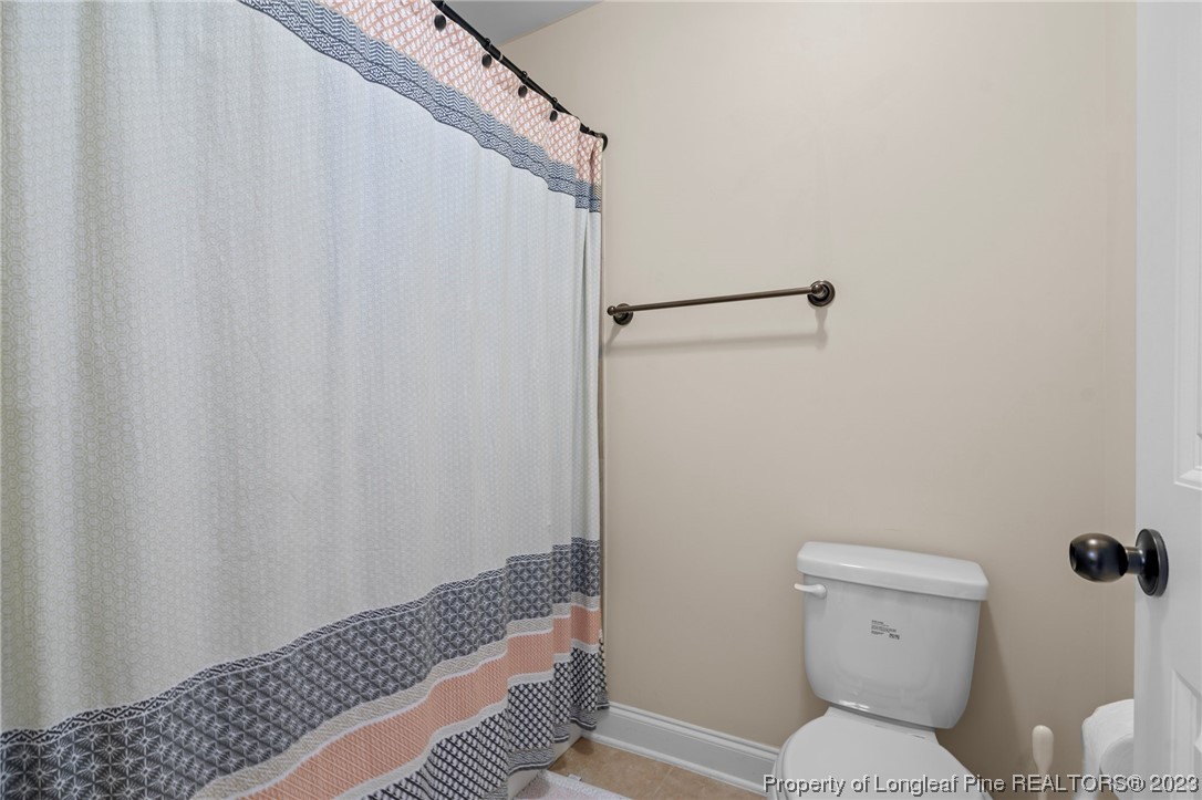 1365 Micahs Way North Spring Lake, NC 28390 - Photo 27 of 36 a bathroom with a toilet and a shower curtain