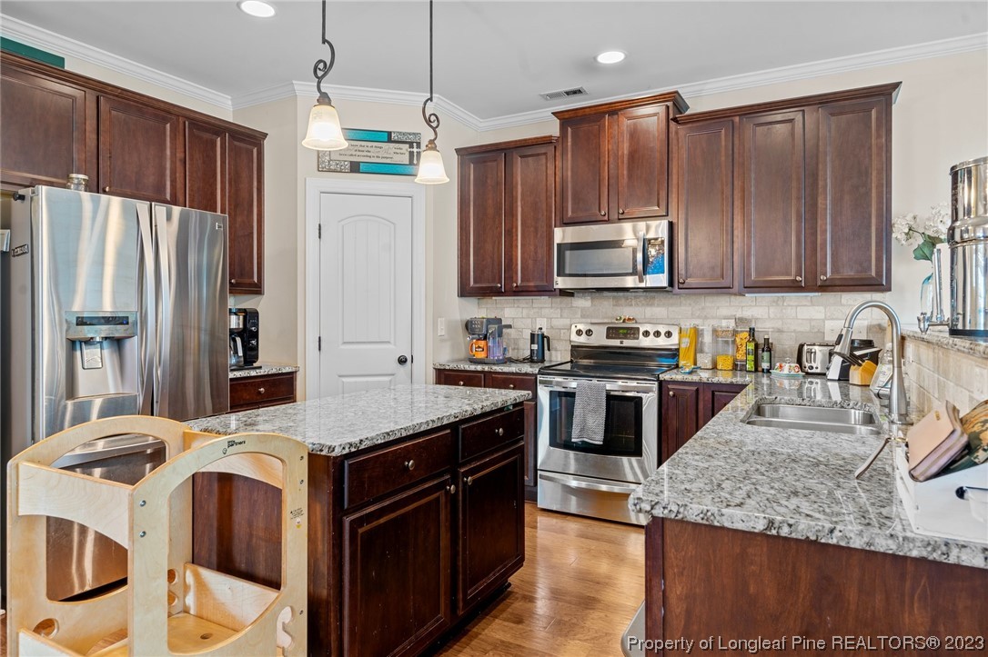 1365 Micahs Way North Spring Lake, NC 28390 - Photo 9 of 36 a kitchen with stainless steel appliances granite countertop a stove a sink and a refrigerator