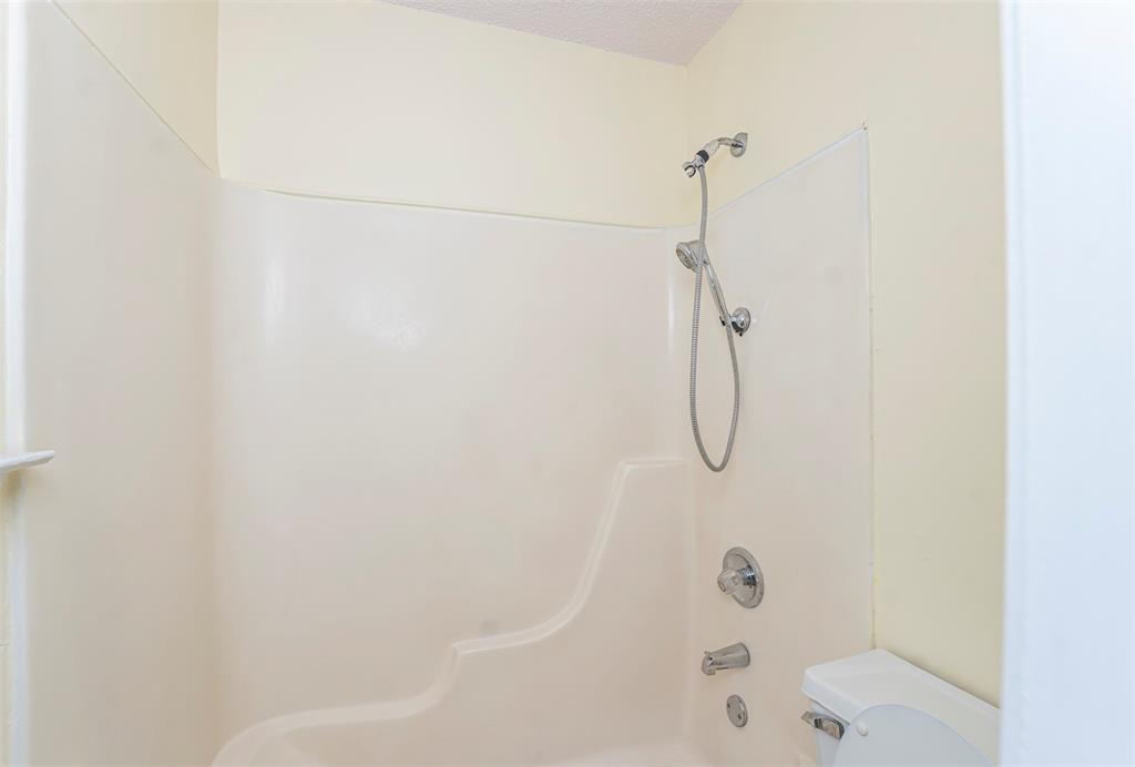 617 Rolling Ridge Court Azle, TX 76020 - Photo 11 of 20 Bathroom featuring a white tub-shower combination unit with integrated shelving, chrome shower fixtures, and a white toilet