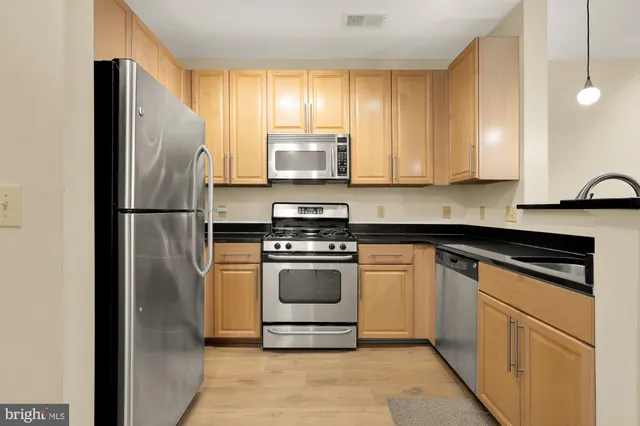 a kitchen with stainless steel appliances granite countertop a refrigerator sink and stove
