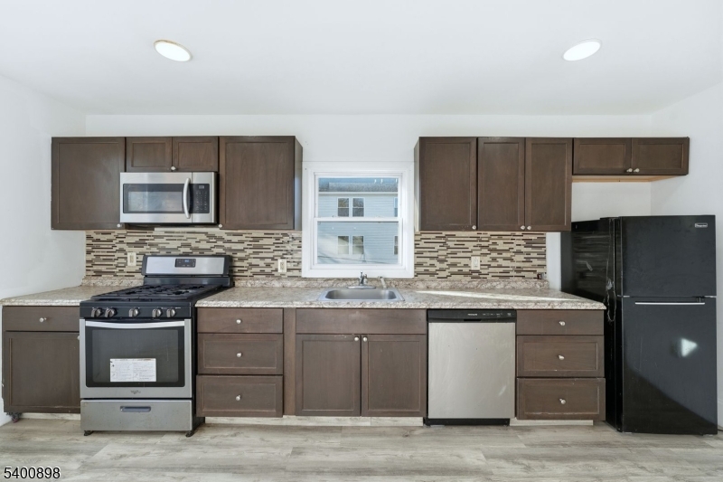 78 South Devine Street Newark, NJ 07106 - Photo 7 of 24 a kitchen with stainless steel appliances granite countertop a stove a sink and a microwave