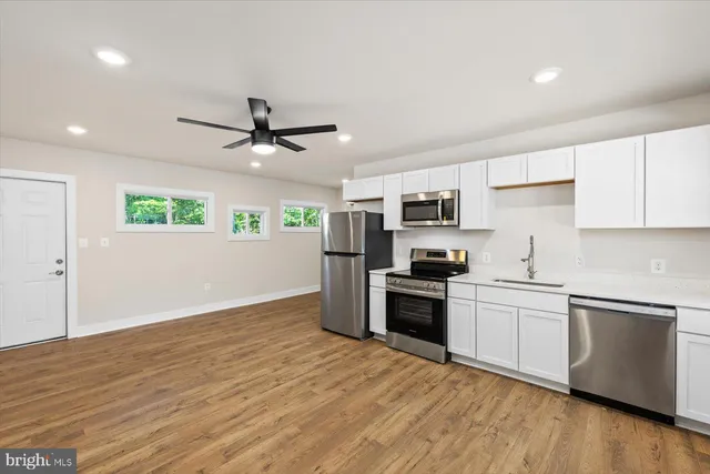 a kitchen with stainless steel appliances granite countertop white cabinets and black stove top oven