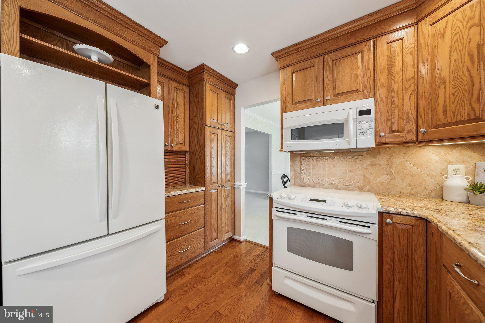 8312 Timber Brook Lane Springfield, VA 22153 - Photo 19 of 42 a kitchen with stainless steel appliances white cabinets and wooden floor