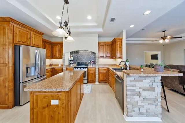 a large kitchen with granite countertop a large counter top appliances and cabinets