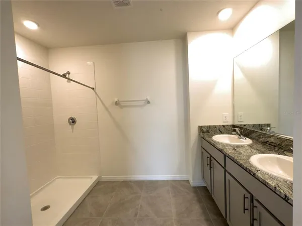 a bathroom with a granite countertop sink a mirror and a shower