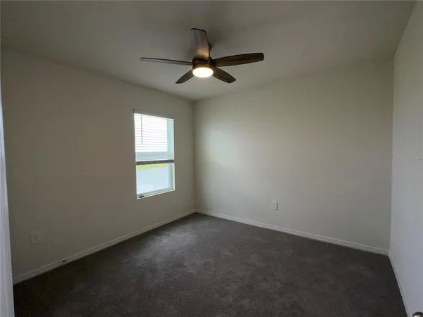 an empty room with a window and a fan