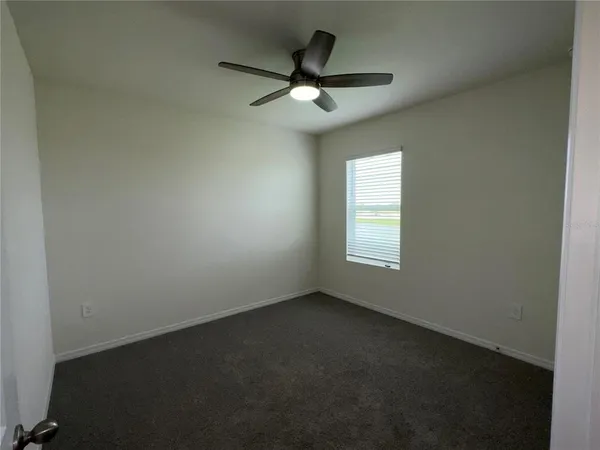an empty room with a window and a fan