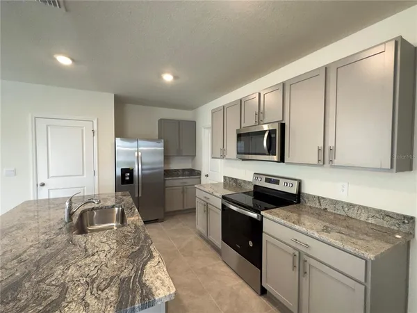 a kitchen with granite countertop a refrigerator stove and microwave