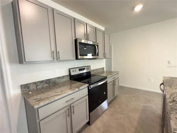 a kitchen with stainless steel appliances granite countertop a stove a sink and a microwave