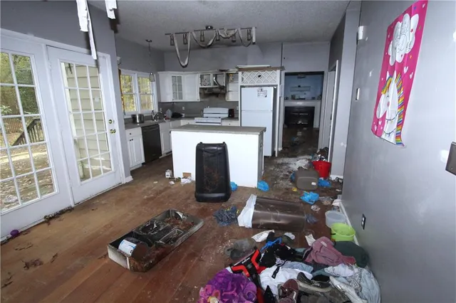 a kitchen with a refrigerator a stove a sink dishwasher a dining table and chairs with wooden floor