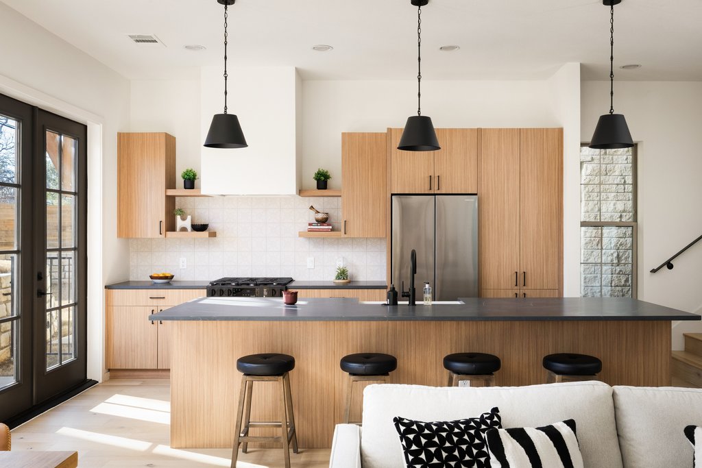 Kitchen has Quartz countertops, open shelving, island with Farmhouse-style sink, light wood finish cabinets, and stainless appliances.
