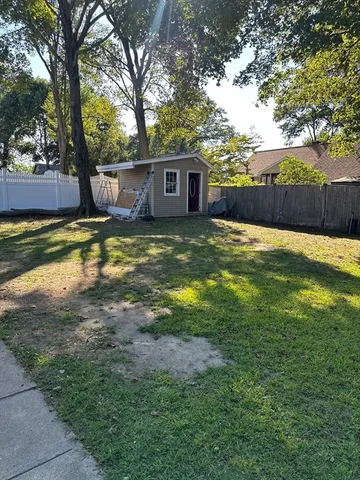 a view of a backyard with large trees and wooden fence