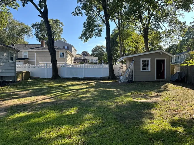 a view of a house with a yard and large tree