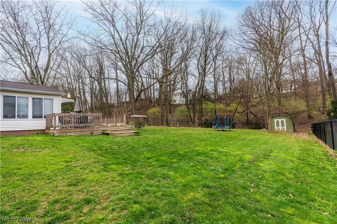 4904 3rd Street Northwest Canton, OH 44708 - Photo 22 of 31 View of yard with a storage shed, a wooden deck, and a trampoline