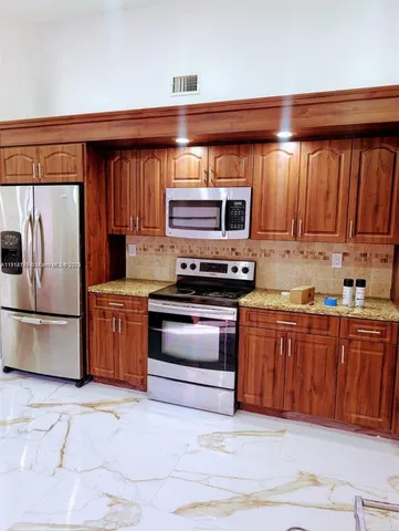 a kitchen with stainless steel appliances granite countertop a stove microwave and refrigerator