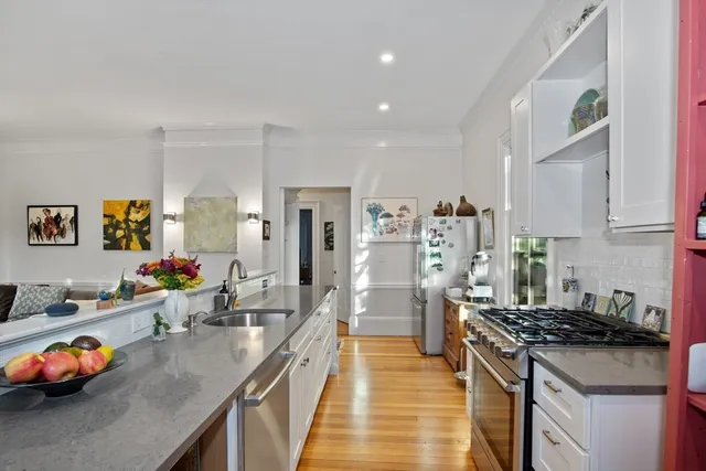 a kitchen that has a lot of cabinets a stove and wooden floor