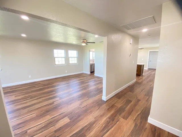 a view of an empty room with wooden floor and a window