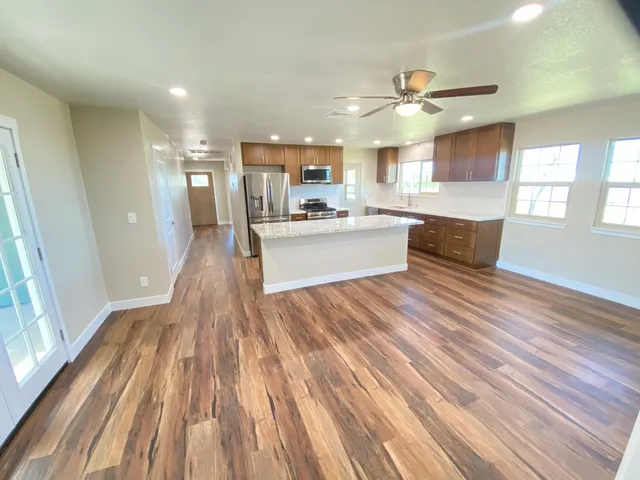 a kitchen with a refrigerator stove and wooden floor
