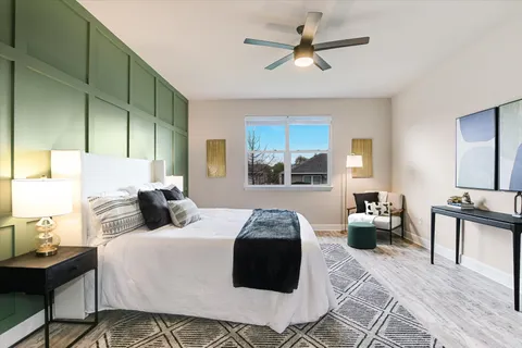 a bedroom with a large bed a chandelier and windows