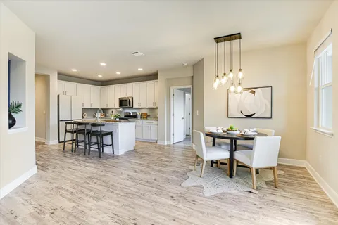 a kitchen with a dining table chairs and refrigerator