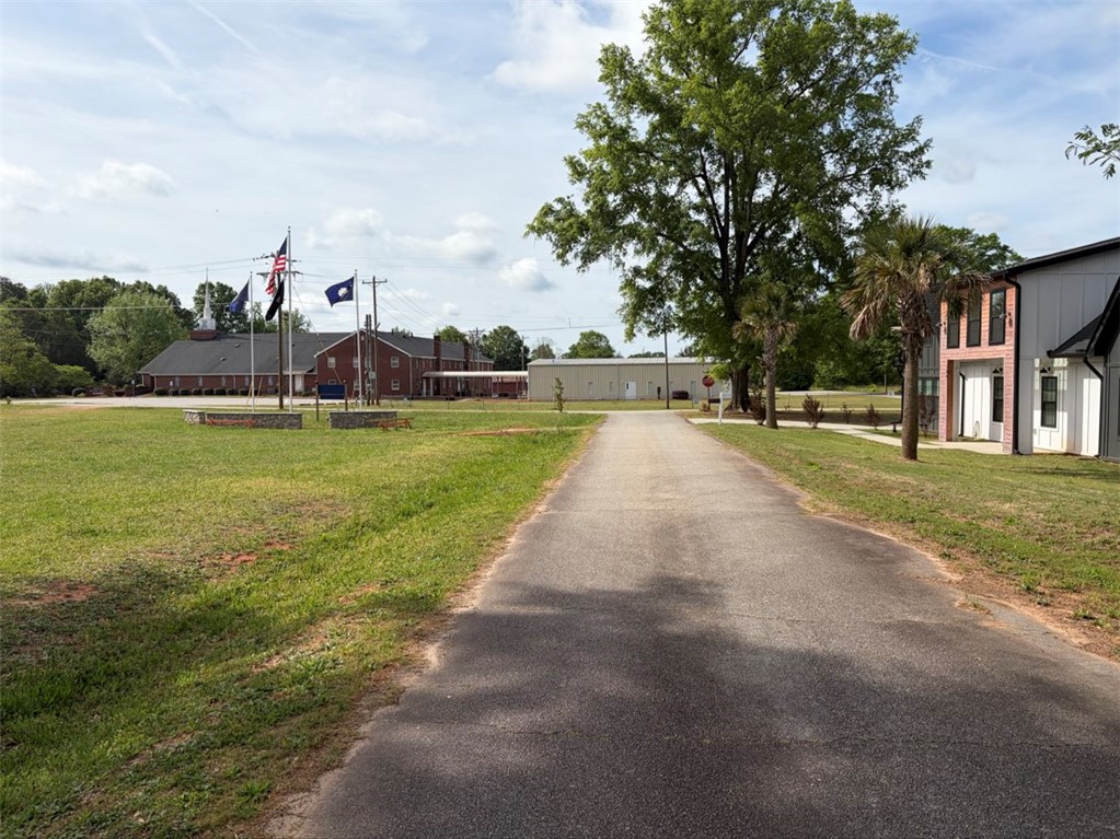 102 Sioux Street Laurens, SC 29360 - Photo 8 of 8 An inviting paved driveway leads to a classic brick structure under a bright sky.