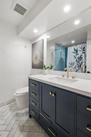 a bathroom with a granite countertop sink mirror vanity and toilet